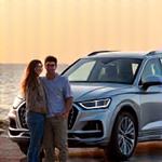 Famille souriante devant un SUV Audi Q5 avec la plage en arrière-plan